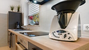 Eine moderne Küche mit Backofen, einer Kaffeemaschine und einem Thermomix Küchengerät.