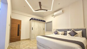 Un dormitorio con cama, ventilador de techo, aire acondicionado, armario y puerta.