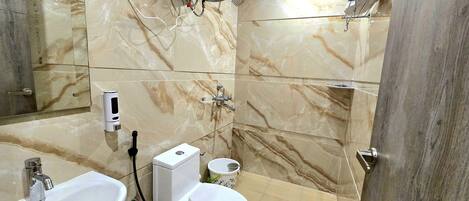 A bathroom with a marble floor, a sink, a toilet, and a shower area.