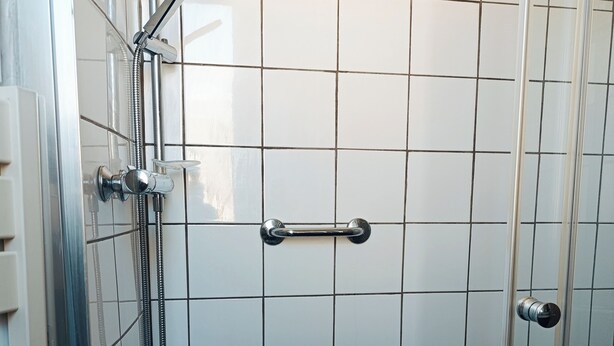 A shower area with a glass door, a handheld showerhead, and a wall-mounted faucet. - Cosy modern cocoon at the foot of Montmartre (Paris)