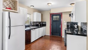 A modern kitchen with white cabinets, a black countertop, and a wooden floor.
