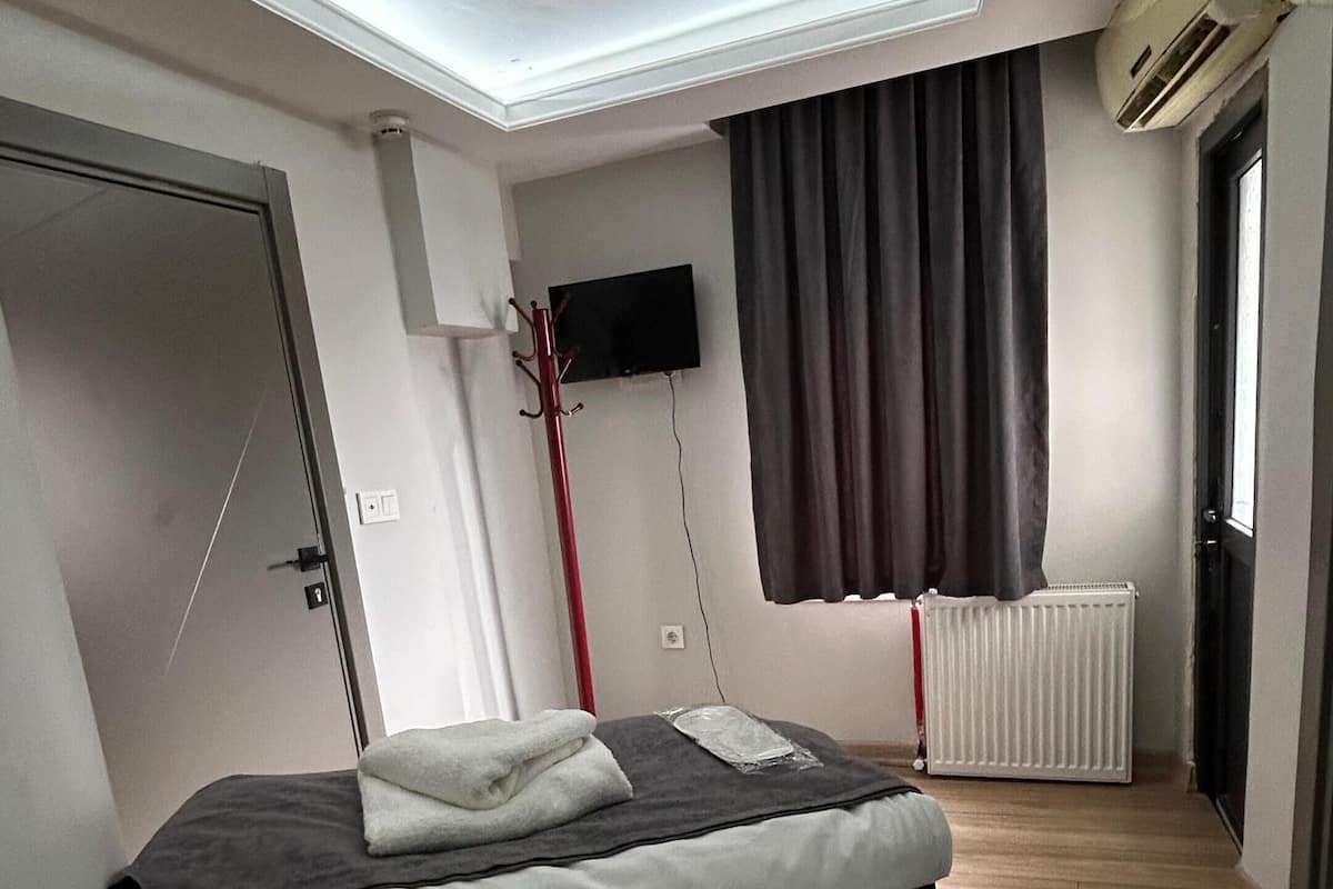 Une chambre moderne avec un puits de lumière, un lit, un téléviseur à écran plat et un radiateur.