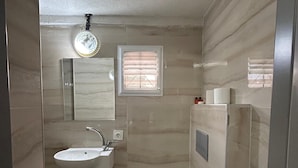 A small bathroom with a sink, toilet, and a window with blinds. - mesil hotel  (Istanbul)