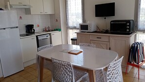 Eine kleine Küche mit weißen Schränken, einer Mikrowelle, einem Toaster und einer Kaffeemaschine.