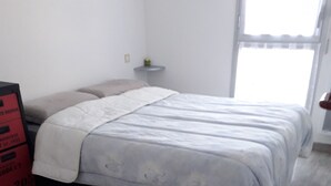 Ein Schlafzimmer mit Bett, Nachttisch und Fenster.