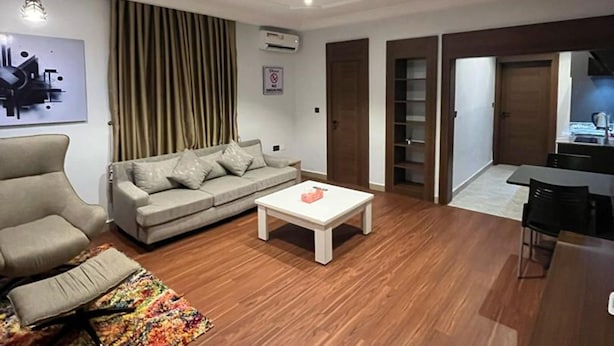 A modern living room with a sofa, a coffee table, and a colorful rug. - Moz One Apartments (Abuja)