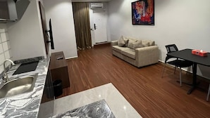 A modern kitchen with a marble countertop and a dining area with a table and chairs. - Moz One Apartments (Abuja)