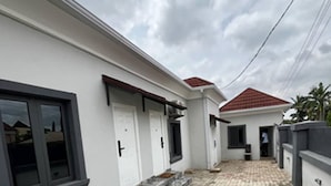 A modern house with a paved courtyard, white exterior walls, and a red-tiled roof. - Moz One Apartments (Abuja)