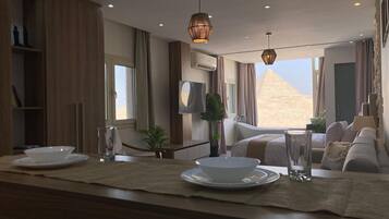A modern hotel room with a large window, a bathtub, a sofa, and a dining area with plates and glasses.