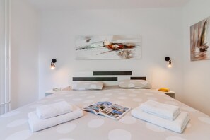 A bedroom with a bed, two bedside tables, a wall-mounted artwork, and a magazine on the bed. - The Green Corner Apartment With Balcony (Zagreb)