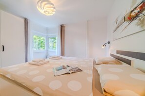 A hotel room with a bed, a window, and a wall-mounted lamp.