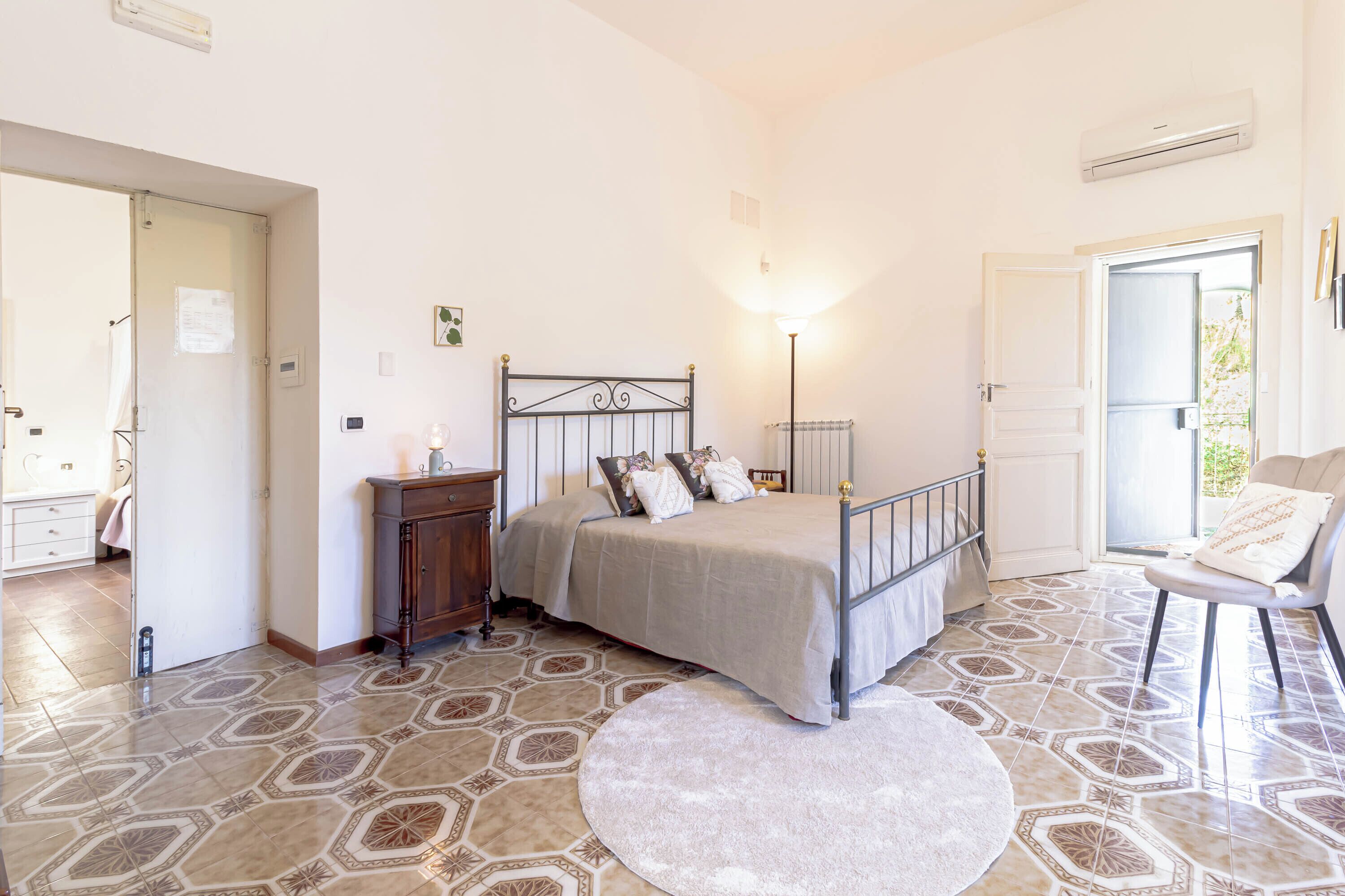 Une chambre à coucher avec un lit, une table de chevet, une lampe et une chaise.