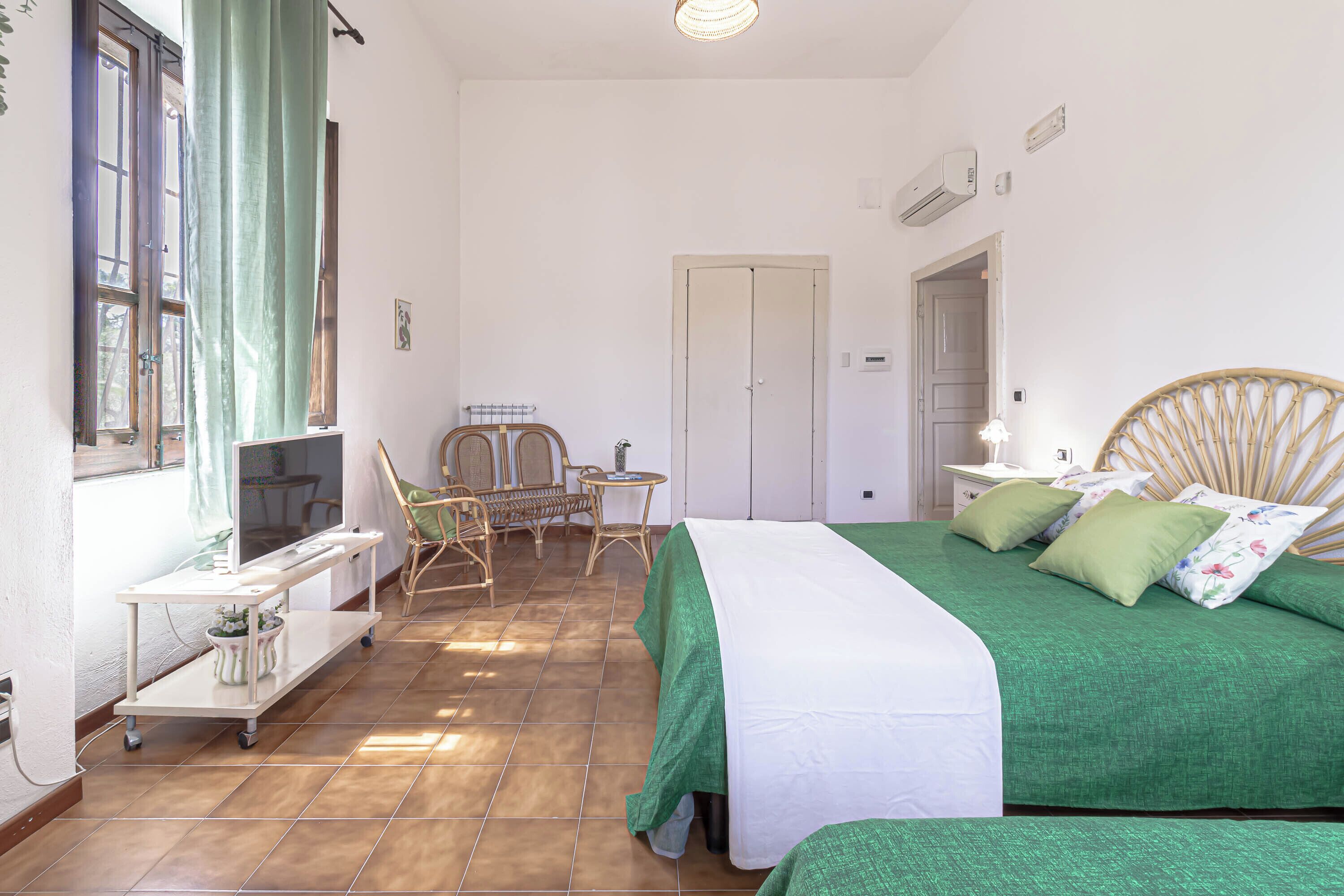 Ein Zimmer mit einem Bett, einem kleinen Tisch, einem Stuhl und einem Fenster mit Vorhängen.
