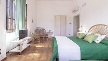 Ein Zimmer mit einem Bett, einem kleinen Tisch, einem Stuhl und einem Fenster mit Vorhängen.