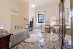 Ein Schlafzimmer mit Bett, Schreibtisch, Stuhl, Fernseher und einem Fenster mit Vorhängen.