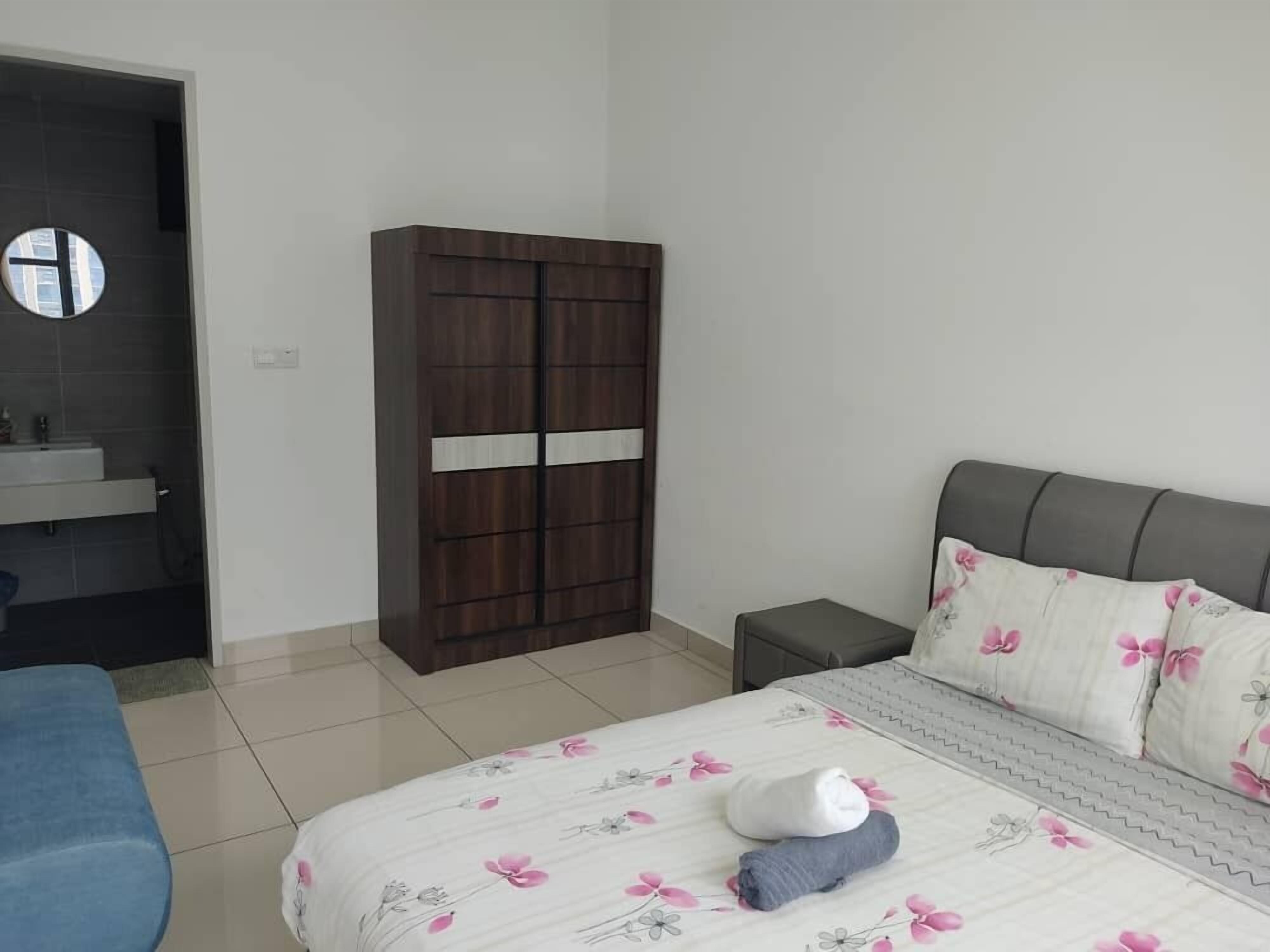 A bedroom with a bed, a wardrobe, a bedside table, and a bathroom visible through an open door.