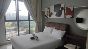 A hotel room with a large bed, a desk, and a view of a cityscape through a large window. - Trion Hotel Suites By Havenza (Kuala Lumpur)