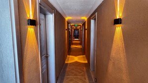 A hotel hallway with doors, wall-mounted lights, and a carpeted floor. - GRAND ALVER OTEL (Edremit)