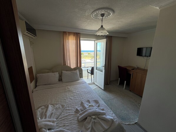 A hotel room with a bed, a desk, a TV, and a view of the outside.