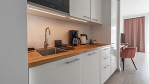 A modern kitchen with a built-in microwave, coffee maker, and sink. - RentPlanet - Apartament Ptasia (Wrocław)