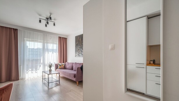 A modern living room with a sofa, a coffee table, and a large wardrobe. - RentPlanet - Apartament Ptasia (Wrocław)