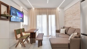 A modern living room with a flat-screen TV, a wooden dining table, a bench, and a sofa.