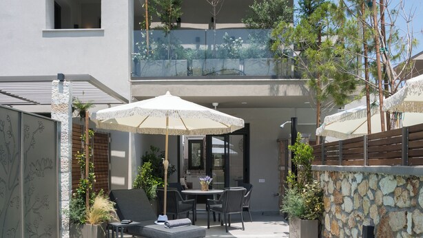 A modern two-story house with a swimming pool, outdoor seating, and a stone wall.