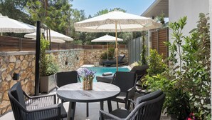 An outdoor patio with a round table and chairs, surrounded by stone walls and covered by large umbrellas.