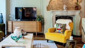 A living room with a television, a fireplace, and a yellow armchair.