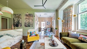 A spacious living room with a marble fireplace, a yellow armchair, and a green sofa.