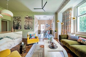 A spacious living room with a marble fireplace, a yellow armchair, and a green sofa.