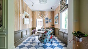 A dining area with striped wallpaper, a checkered floor, and a chandelier.