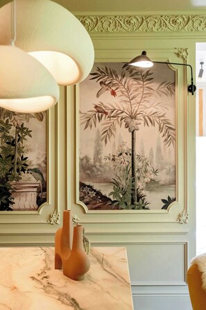 A room with a mural, a hanging light fixture, and a marble countertop with vases.