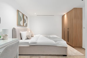 A modern bedroom with a bed, bedside table, lamp, and a wardrobe. - Modish 2BR at Elite Residences (Dubai)