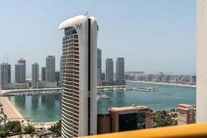 A high-rise hotel with a distinctive curved top, a marina with boats, and a cityscape in the background. - Modish 2BR at Elite Residences (Dubai)