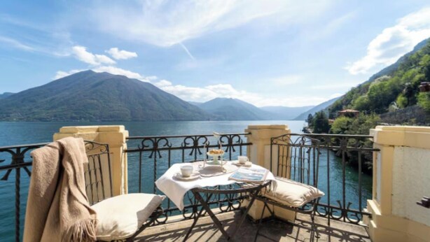 A balcony with a table set for two, overlooking a lake and mountains. -  A Vintage Jewel with Panoramic Lake Views (Argegno)