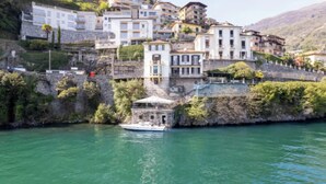 A coastal town with historic buildings, a boat docked near the shore, and a stone wall. -  A Vintage Jewel with Panoramic Lake Views (Argegno)