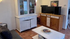 Ein Wohnzimmer mit einem weißen Schrank, einem Fernseher und einem Couchtisch.