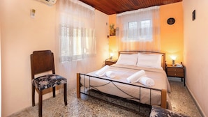 Een slaapkamer met een bed, een stoel, een nachtkastje en een wandairconditioner.