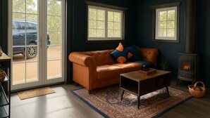A living room with a leather sofa, a coffee table, a rug, and a wood-burning stove. - Secluded Forest Retreat (MOONDYNE)