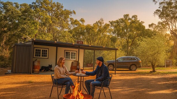 Two people seated at a table with a fire pit in a rustic outdoor setting, a car, and a small building in the background. - Secluded Forest Retreat (MOONDYNE)