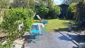 Eine Terrasse mit Tisch und Stühlen, umgeben von Grünpflanzen und einem Garten.