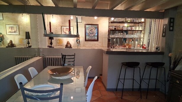 Ein Essbereich mit einem Glastisch und Stühlen, eine Bar mit Hockern und ein gefliester Boden.