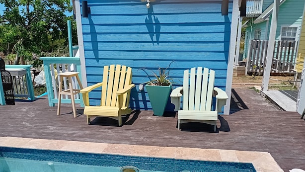 Een zwembadgedeelte met twee Adirondack-stoelen, een potplant en een blauwe muur op de achtergrond.
