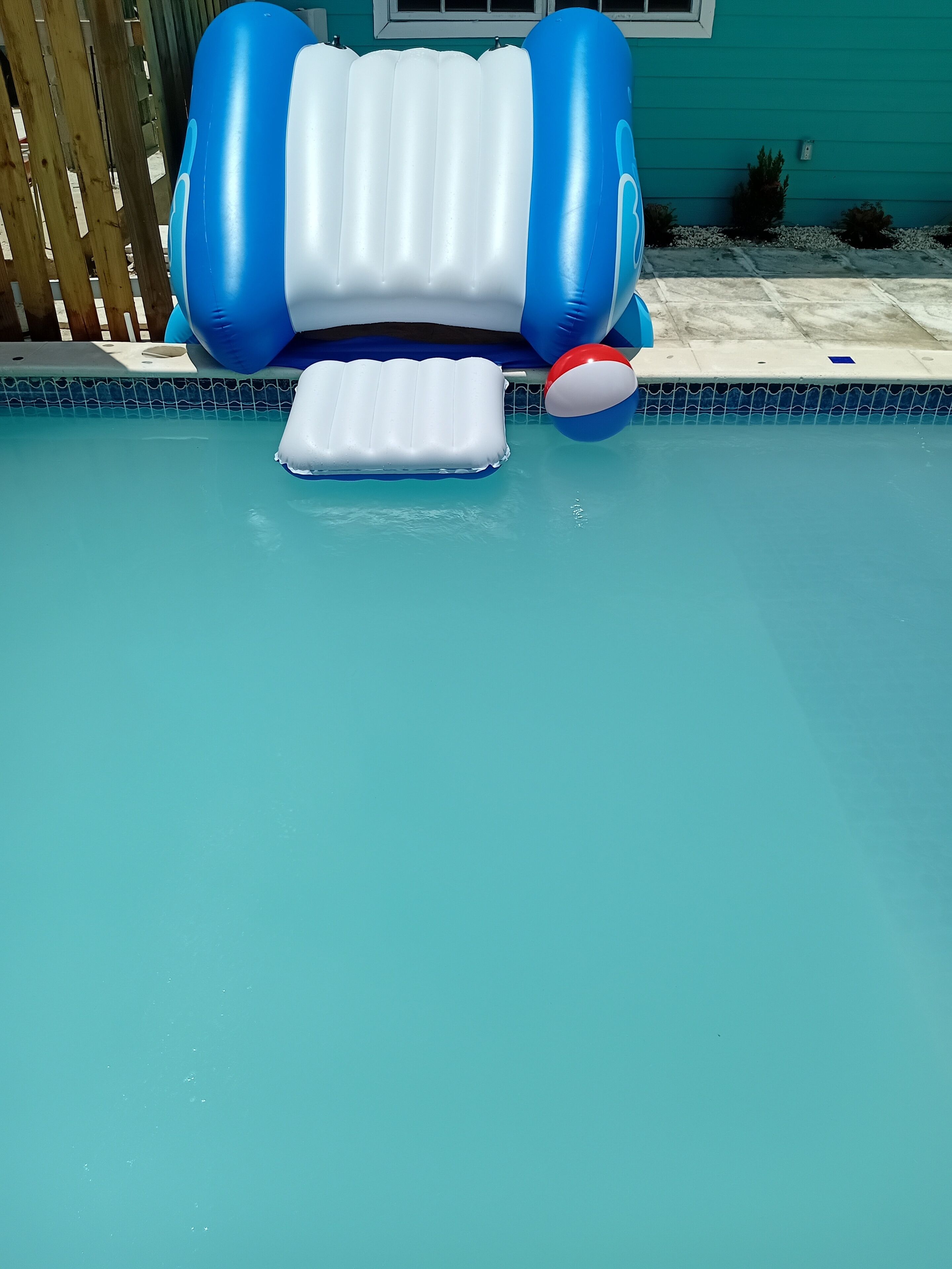 Une piscine avec des jouets gonflables et une clôture en bois en arrière-plan.
