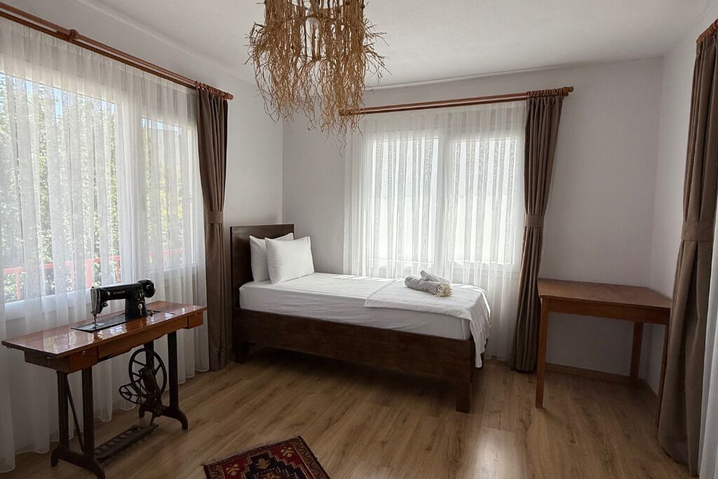 A bedroom with a wooden bed, a sewing machine, and a small wooden table.