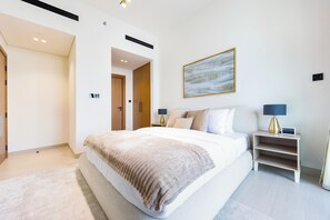 A modern bedroom with a large bed, bedside tables, a painting, and a ceiling vent. - Bloomfields Modern 1Br Binghatti ONYX  (Dubai)