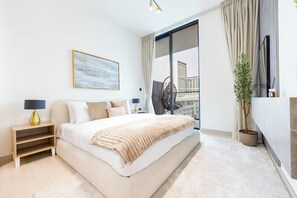 A modern bedroom with a large bed, a bedside table with a lamp, a window with curtains, and a view of buildings. - Bloomfields Modern 1Br Binghatti ONYX  (Dubai)