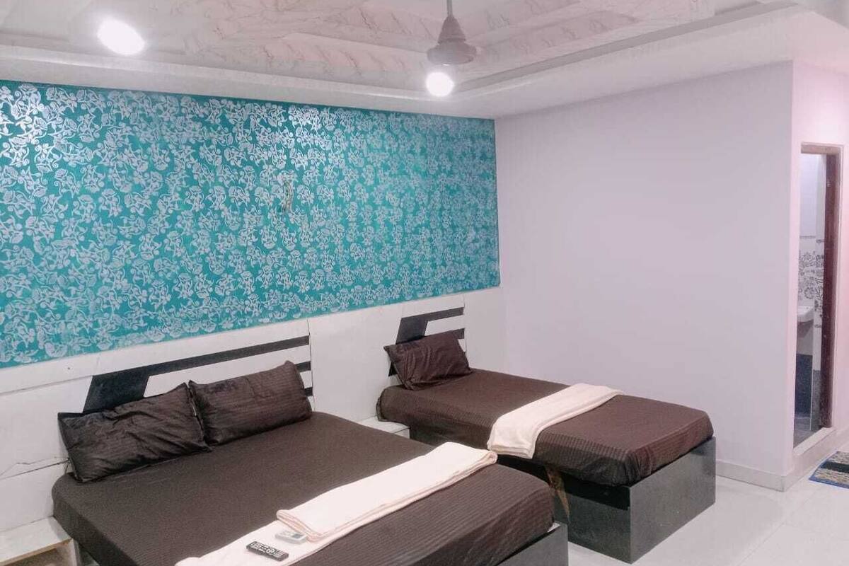 A bedroom with two beds, a patterned wall, and a ceiling fan.