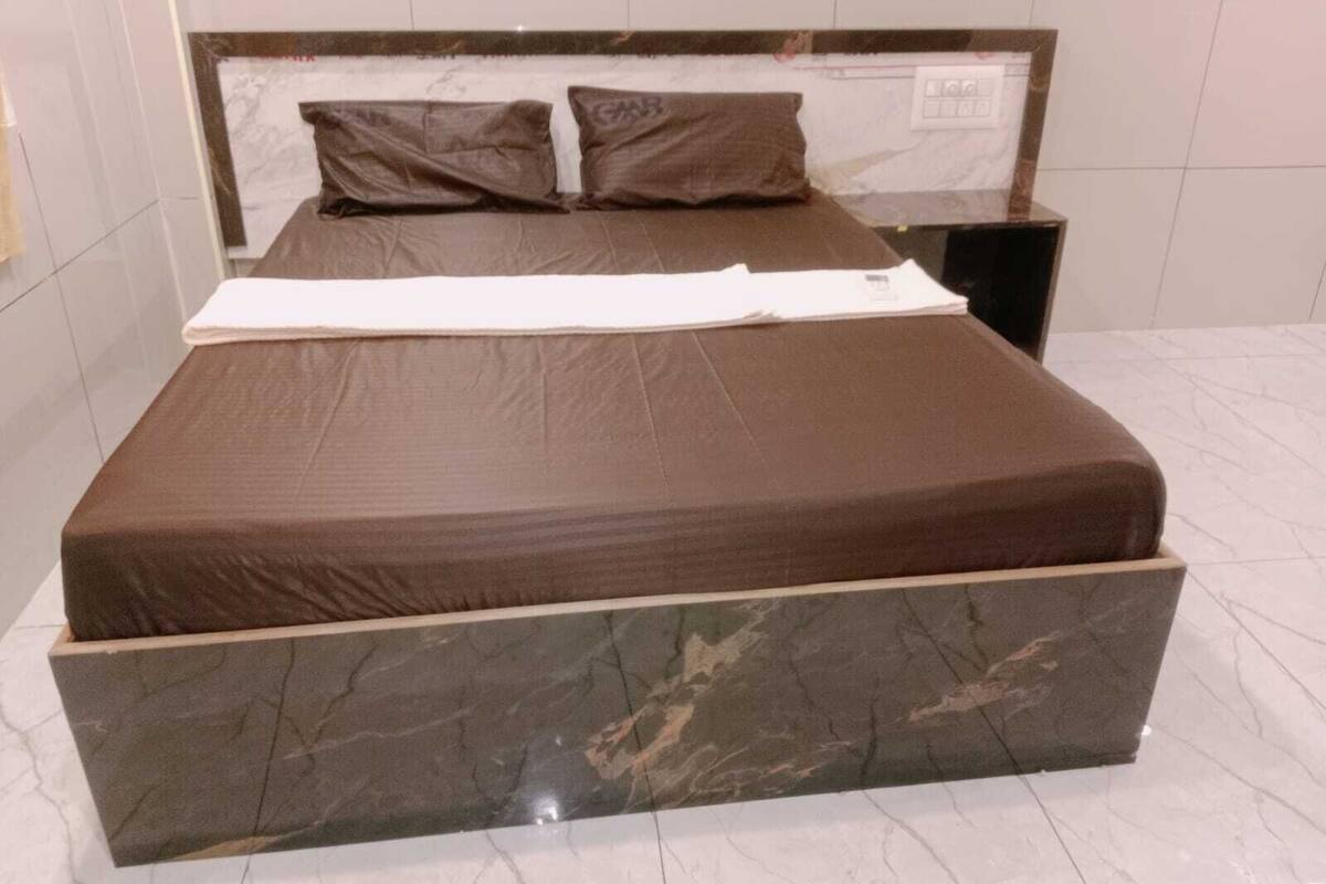 A large bed with a marble headboard and footboard, a white blanket, and two pillows.